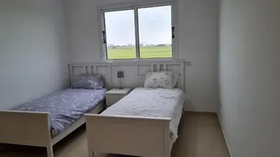 two beds in a small room with a window at The Olive Grove Escape, Eleonas Apts in Sotira