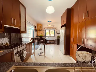 a kitchen with wooden cabinets and a dining room at House of Hera in Livadhia