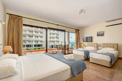 a bedroom with two beds and a large window at Seafront Protaras Villas in Protaras