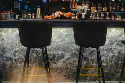 a bartender standing behind a bar with two chairs at The Ciao Stelio Deluxe Boutique Hotel - Adults Only in Larnaka