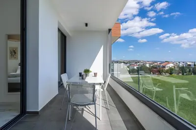 a balcony with a table and chairs and a large window at Ivory 1-BR Apartment in Aradipou in Aradhippou