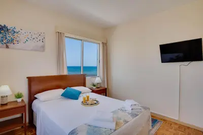 a bedroom with a bed with a view of the ocean at Makenzy Sandy Beachfront Paradise in Larnaka