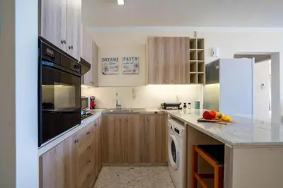 a kitchen with wooden cabinets and a sink and a dishwasher at Makenzy Sandy Beachfront Paradise in Larnaka
