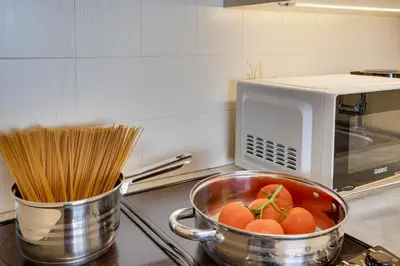 a pot of tomatoes and pasta in front of a microwave at Makenzy Sandy Beachfront Paradise in Larnaka