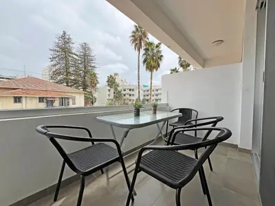 a table and chairs on a balcony with a view at Albert's Apartment Center 202B in Larnaka