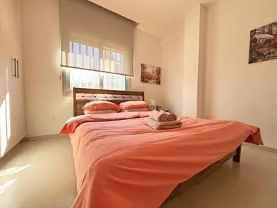 a bedroom with a large bed with orange sheets and pillows at Albert's Apartment Center 202B in Larnaka