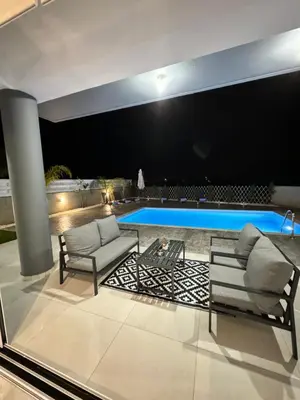 a living room with two chairs and a swimming pool at Protaras Rustic Paradise Luxury Villa 1 in Paralimni