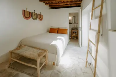 a white bedroom with a bed and a ladder at Smaragda's Guest Rooms in Limassol