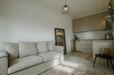 a living room with a white couch and a kitchen at Smaragda's Guest Rooms in Limassol