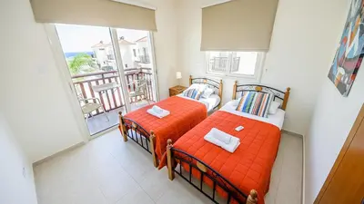 two beds in a room with a balcony at Kapparis Holiday Villa 018 in Protaras