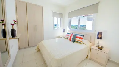 a white bedroom with a bed and a window at Pernera Holiday Villa 012 in Protaras