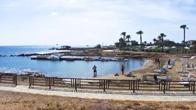 a beach with palm trees and people and the ocean at Pernera Holiday Villa 012 in Protaras