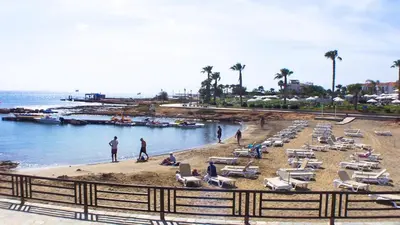 a beach with chaise lounges and people on the beach at Pernera Holiday Villa 012 in Protaras