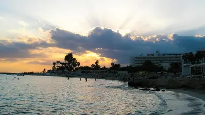 a beach with people swimming in the water at sunset at Ayia Napa Holiday Villa 003 in Ayia Napa