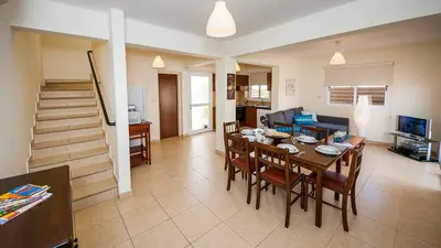 a dining room and living room with a table and chairs at Ayia Napa Holiday Villa 003 in Ayia Napa