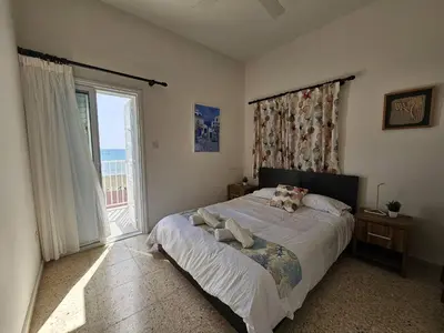 a bedroom with a bed and a large window at Ammos Beachfront Villa Paradise in Larnaka
