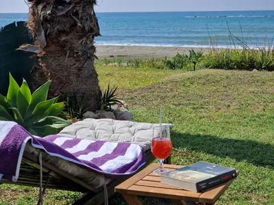 a table with a book and a glass of wine at Ammos Beachfront Villa Paradise in Larnaka