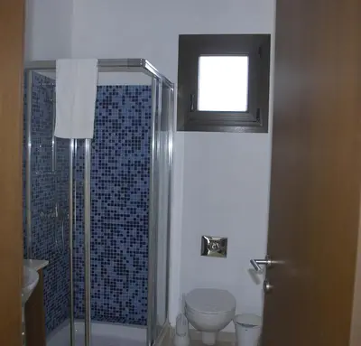 a bathroom with a shower and a toilet and a window at Summer Breeze in Paralimni