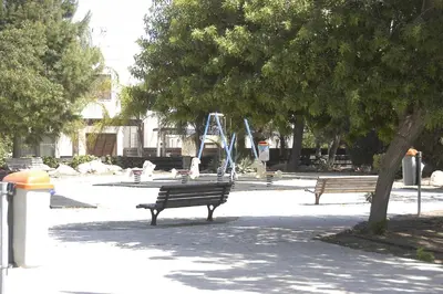 two benches in a park with trees and a playground at Summer Breeze in Paralimni