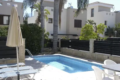 a pool with chairs and an umbrella next to a building at Summer Breeze in Paralimni