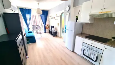 a kitchen with white appliances and a living room at 2Br Apt Coastal Comfort with Internet Access in Larnaka