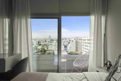 a bedroom with a large window with a view of a city at Phaedrus Living Limassol Seaside Residences 06 in Limassol