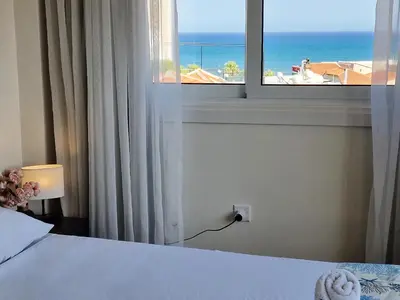 a bedroom with a window with a view of the ocean at Kitieos Central Apartment with Sea View in Larnaka