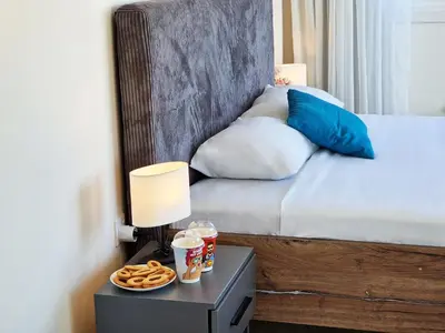 a bed with a side table with a lamp and pretzels at Kitieos Central Apartment with Sea View in Larnaka