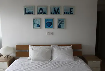 a bedroom with a bed with four pictures on the wall at The Olive Tree in Protaras