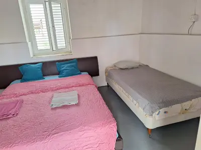 two beds in a room with pink sheets and blue pillows at Room with private entrance from outside, traditional house in Livadhia