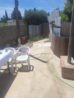 a patio with two white chairs and a hose at Room with private entrance from outside, traditional house in Livadhia