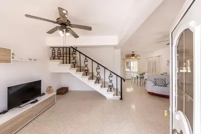a living room with a staircase and a ceiling fan at Ayia Thekla Sea Breeze Villa in Ayia Napa