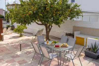 a table and chairs under an orange tree on a patio at Ayia Thekla Sea Breeze Villa in Ayia Napa