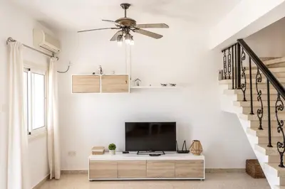 a living room with a tv and a staircase at Ayia Thekla Sea Breeze Villa in Ayia Napa