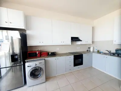 a kitchen with white cabinets and a washing machine at Aphrodite Heights in Larnaka