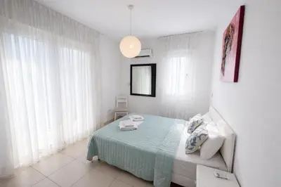 a white bedroom with a bed and a pendant light at Villa Dolce Vita in Protaras