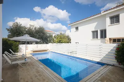 a swimming pool with an umbrella and a house at Protaras Serifos Villa Sv07 in Paralimni