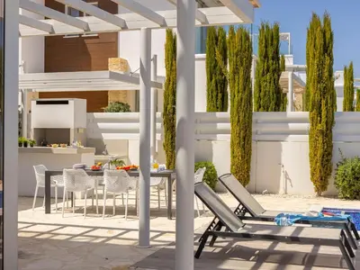 a patio with chairs and a table and a dining area at Villa Natalie-Mylos H24 in Protaras