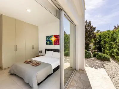 a bedroom with a bed and a large glass window at Villa Natalie-Mylos H24 in Protaras