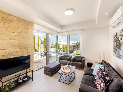 a living room with a couch and a tv at Villa Natalie-Mylos H24 in Protaras