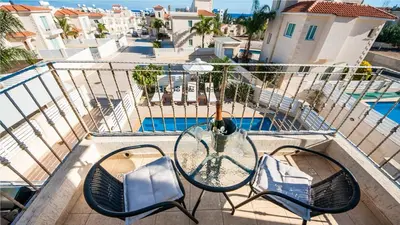 a balcony with a glass table and chairs and a pool at Protaras Holiday Villa 045 in Protaras