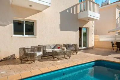 a patio with a table and chairs next to a pool at Protaras Holiday Villa 035 in Protaras