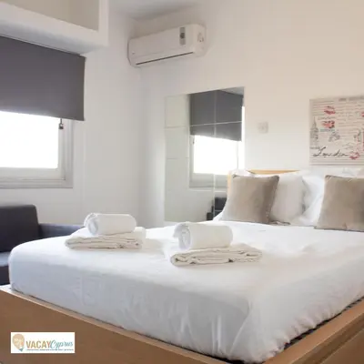 a bedroom with a large white bed with towels on it at Downtown Larnaca Apartment in Larnaka