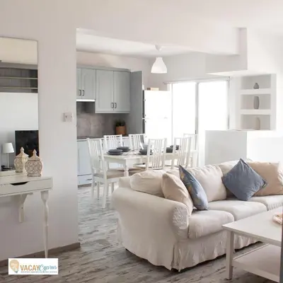 a white living room with a white couch and a kitchen at Downtown Larnaca Apartment in Larnaka