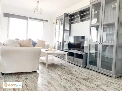 a living room with a white couch and a tv at Downtown Larnaca Apartment in Larnaka