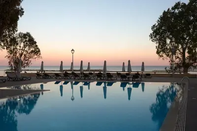 a swimming pool with chairs and the ocean in the background at Harmony Bay Hotel in Limassol