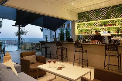 a restaurant with a bar with glasses of wine at Harmony Bay Hotel in Limassol