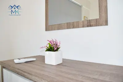 a bathroom counter with a mirror and flowers on it at SeaWitch Apartment in Larnaka