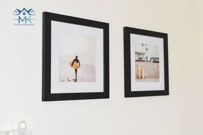 two framed pictures of a man with a surfboard on a wall at SeaWitch Apartment in Larnaka