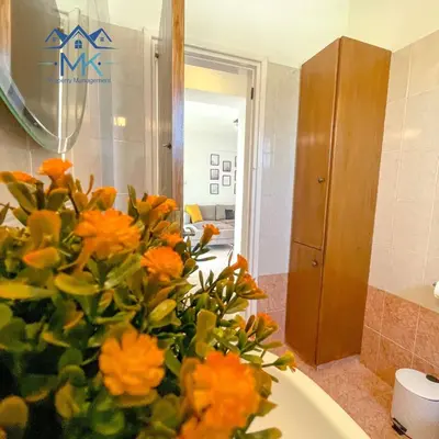 a bathroom with a bouquet of orange flowers in a sink at SeaWitch Apartment in Larnaka
